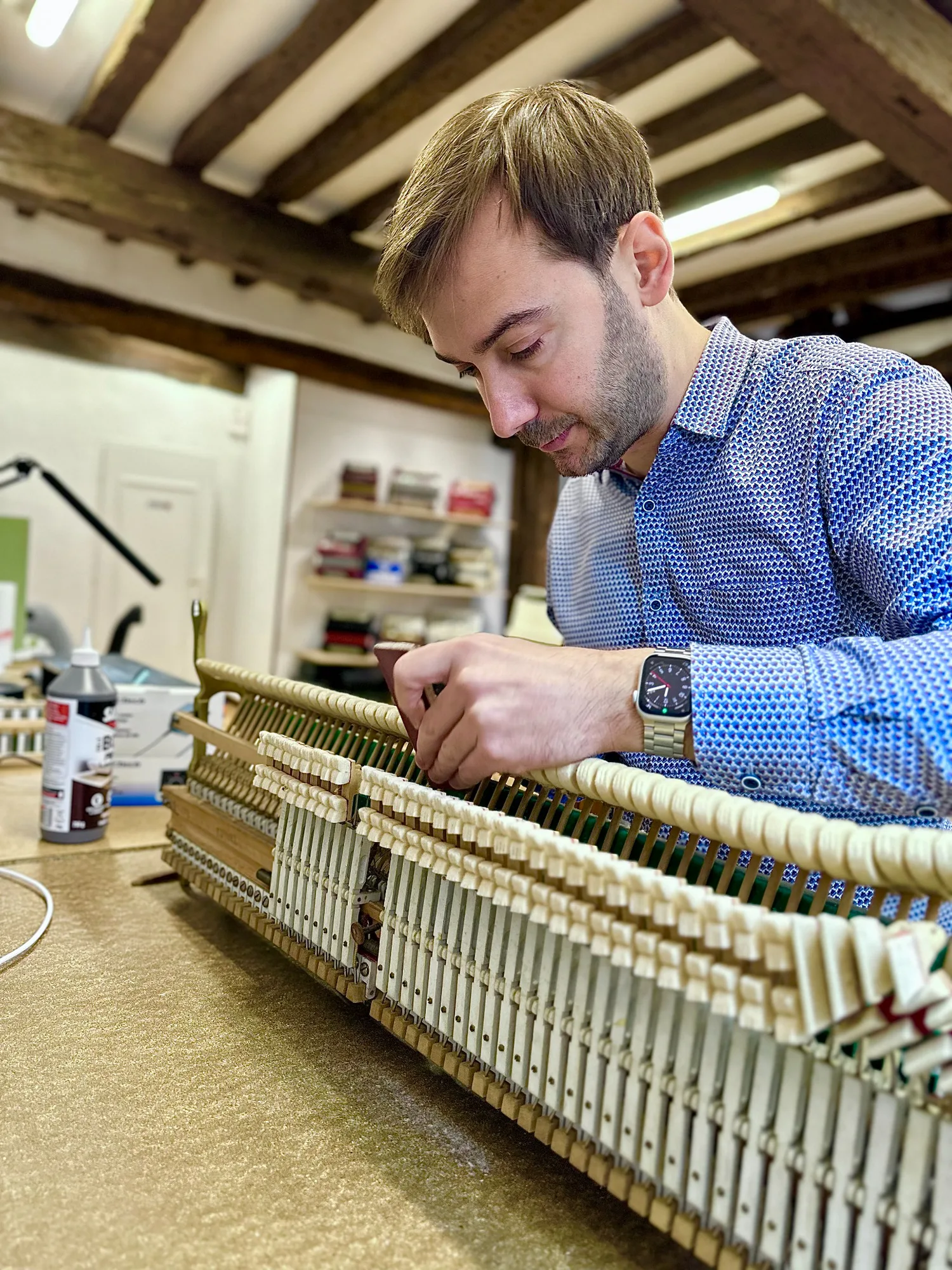 Simon Boulé travaille avec précision sur la mécanique d’un piano à l’atelier