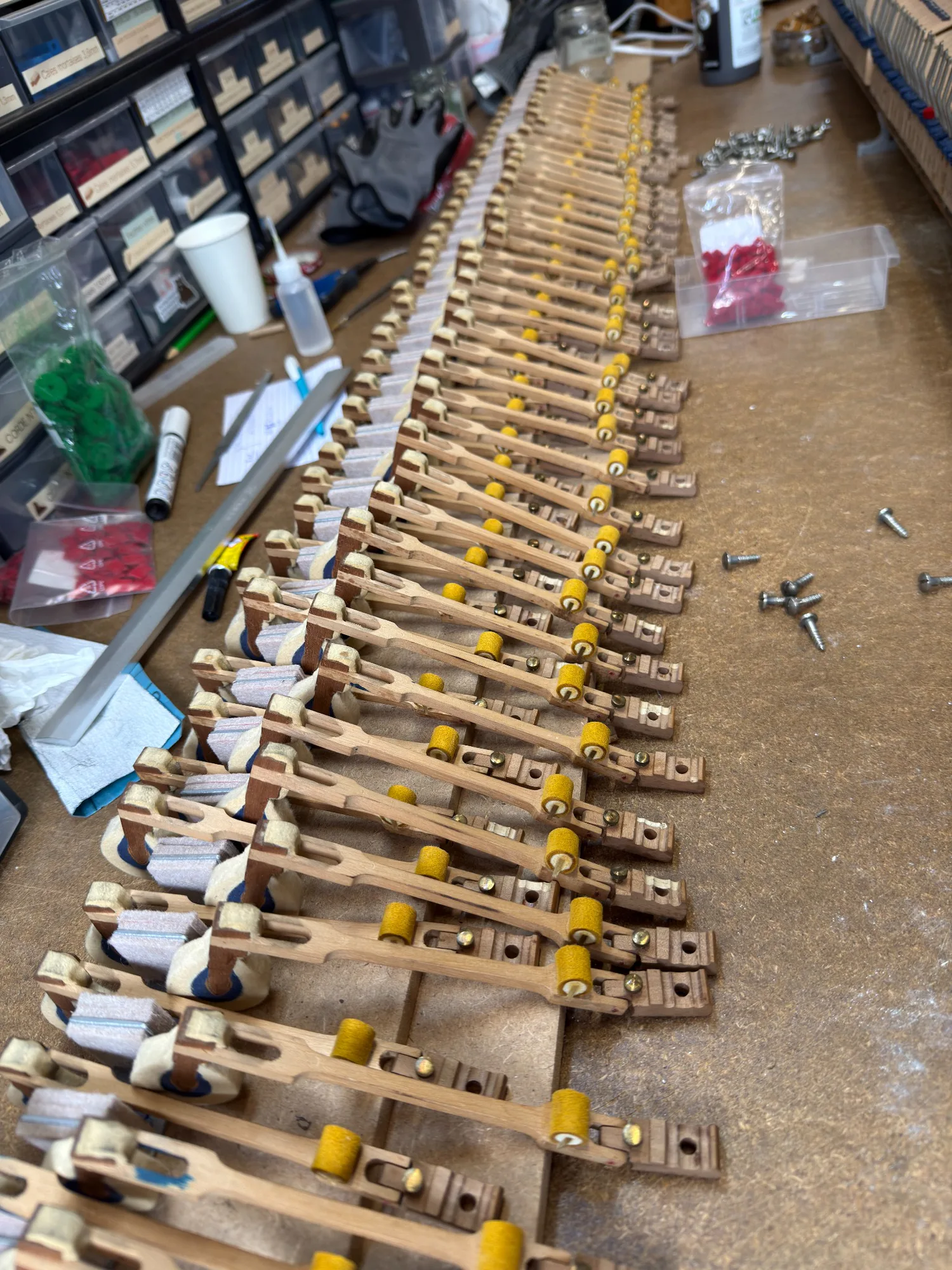 Pièces d’une mécanique de piano démontées et alignées pendant leur restauration